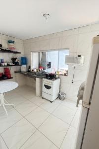 a white kitchen with a stove and a sink at Sobrado Maré Mansa in Peruíbe