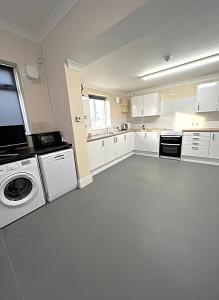 a kitchen with white cabinets and a washer and dryer at Atherley House - Winter Sale! Spacious Self Catered Rooms in Southampton