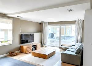 a living room with a couch and a tv at Luxe Villa Tramonto with jacuzzi in Sint-Truiden