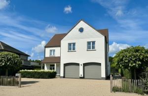 a white house with a two car garage at Luxe Villa Tramonto with jacuzzi in Sint-Truiden
