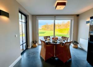 a dining room with a table and chairs and a large window at Luxe Villa Tramonto with jacuzzi in Sint-Truiden