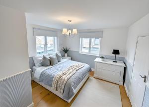 a white bedroom with a bed and two windows at Luxe Villa Tramonto with jacuzzi in Sint-Truiden +33 photos
