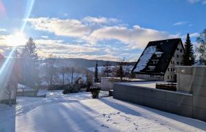 a house in the snow with the sun behind it at Wohnen am Wald mit Pool & Sauna in Unterkirnach