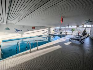 a swimming pool with two benches in a building at Wohnen am Wald mit Pool & Sauna in Unterkirnach