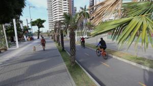 a group of people riding bikes down a street with a dog at 1 Quarto passos da praia in Fortaleza