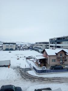 a parking lot with snow on the ground and buildings at Zen aeroport in Sînnicoară