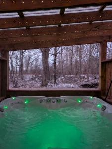 a jacuzzi tub under a wooden roof with green lights at Field and Fern Cottages in Tatamagouche