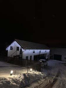 a white building at night with snow on the ground at The Forest Nest Apartment in Sărmaş