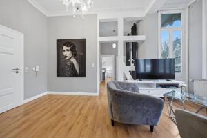 a living room with a television and a chair at EUPHORAS - Central & Stylish Apartment - Parking in Bad Harzburg
