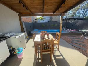 a table and chairs on a patio with a roof at Excelente casa com piscina próx ao Mar in Capão da Canoa