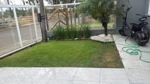 a yard with a tree and a green hose at Excelente casa com piscina próx ao Mar in Capão da Canoa