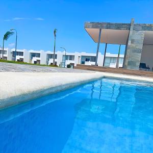 a blue swimming pool in front of a building at Casa Familiar a Pasos del Mar Playa y Felicidad in Manta