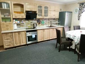 a kitchen with wooden cabinets and a table and a table and chairs at Котедж Тиша in Rivnya +21 photos