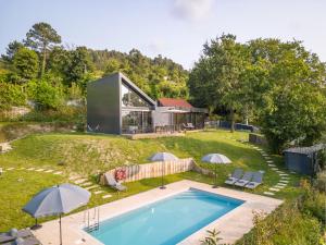 a house with a swimming pool in a yard with umbrellas at Casas De Bouro 3 Casa Do Alecrim in Terras de Bouro