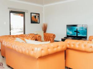 a living room with two leather couches and a tv at Kwagae farm in Kuruman