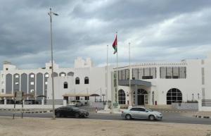 a white building with cars parked in front of it at Resort Sur Beach Holiday in Sur
