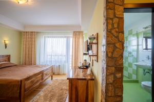 a bedroom with a bed and a bathroom with a sink at Pensiunea Valceaua Zanelor in Stațiunea Climaterică Sâmbăta