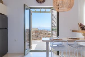 a dining room with a table and chairs and a window at White Cliff Villas Paros in Ambelas