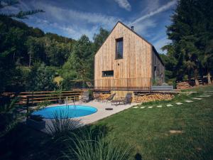 a large wooden barn with a pool in the yard at Chalet Plechovka in Frýdštejn