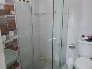 a bathroom with a glass shower with a toilet at Flats Mundos Golfinhos in Pipa