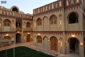 a large building with arches and a courtyard at Nefertari Palace apartments in Al Aqālitah