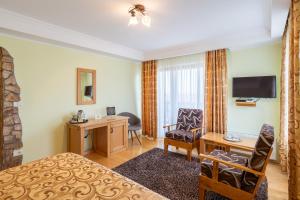 a hotel room with a bed and a desk and a chair at Pensiunea Valceaua Zanelor in Stațiunea Climaterică Sâmbăta