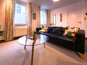 a living room with a black couch and a glass table at Au Petit Pierrot in Spa