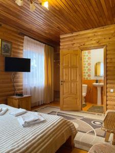 a bedroom with a bed and a television and a bathroom at Karpatska Mria in Yaremche