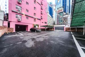 a pink building with a car parked in a parking lot at MoMo Juice Busan Haeundae in Busan
