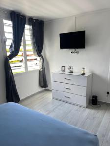 a bedroom with a bed and a dresser with a television at Appartement Acajou Pool & Serenity in Le Lamentin