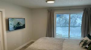 a bedroom with a bed and a window with snow at True Ski-In-Ski-Out Rare 3-Bed Condo in Mount Washington +1 photo