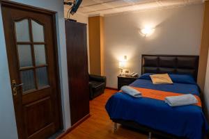 a bedroom with a bed with a blue comforter at Hostal Tukos La Casa Real in Potosí