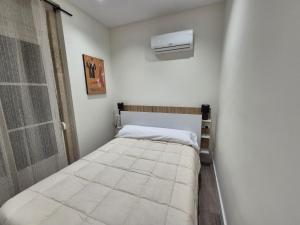 a small bedroom with a bed and a air conditioner at Escola in Ourense