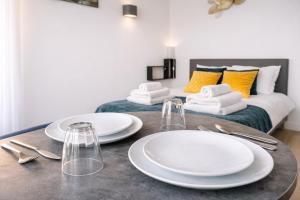 two white plates on a table in front of a bed at L'Agapanthe - Proche Gare in Saint-Pierre-des-Corps