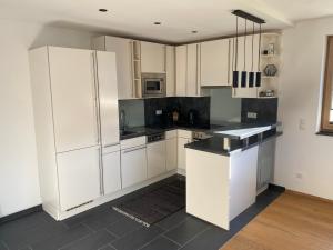 a kitchen with white cabinets and a black counter top at Ferienwohnung Fotscherblick in Sellrain +26 photos