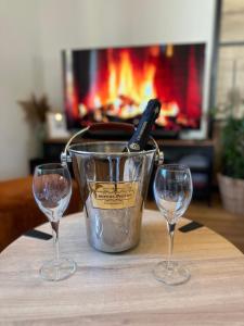 three wine glasses and a bucket on a table with a fireplace at Le Cocon de Vlinette in Brienne-le-Château