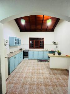 a large kitchen with blue cabinets and a wooden ceiling at Hikka Magnoon Villa in Hikkaduwa