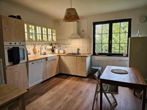 a kitchen with wooden floors and a table and a refrigerator at Kakasvári Vendégház in Gömörszőlős