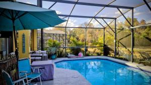 a swimming pool with an umbrella and a patio at NO DAY OF BOOKING 24 HOURS NOTICE One private Master Efficency Suite Room with Bathroom for one person or couple with a pool breakfast included message here or email Floridastylz74 g mail com in Davenport