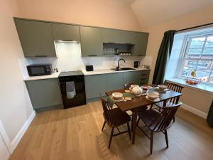 a kitchen with a table and chairs and a kitchen with green cabinets at Roods Apartment in Angus +20 photos