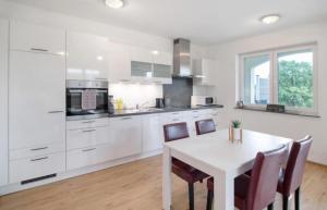 a white kitchen with a white table and chairs at Ferienhof Broger FeWo Bergblickle mit Pool in Neukirch