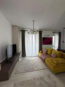 a living room with a yellow couch and a flat screen tv at Deluxe 3 in Timişoara