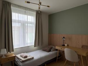 a bedroom with a bed and a desk and a window at De Bakelijn in Nieuwpoort