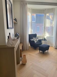 a living room with a blue chair and a couch at De Bakelijn in Nieuwpoort