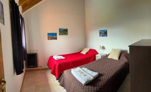 two beds in a small room with red sheets at Buena Vista Trevelin II in Trevelín
