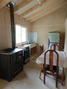 a kitchen with a stove and a table and a sink at Cabaña Mañihueico in Hualaihué