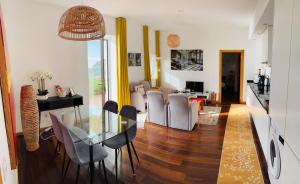 a dining room and living room with a glass table and chairs at Villa Escola da Bica in Arco da Calheta