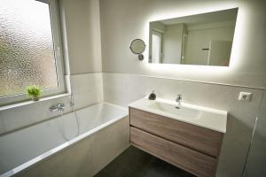 a bathroom with a sink and a tub and a mirror at *Premium-Apartment im Spreewald* in Burg +14 photos