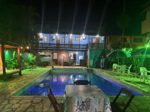 a swimming pool at night with a table in front of a house at POUSADA BELLA SPIAGGIA in Paraty