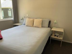a bedroom with a bed with white sheets and a window at Relax in the Garden Suite in Thames